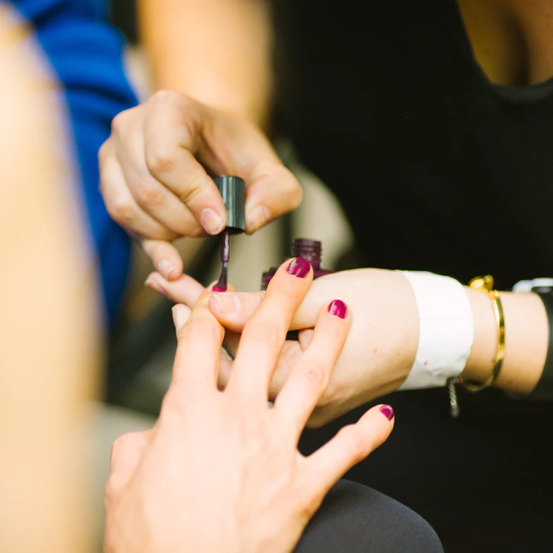 Manicurist applying deep red polish